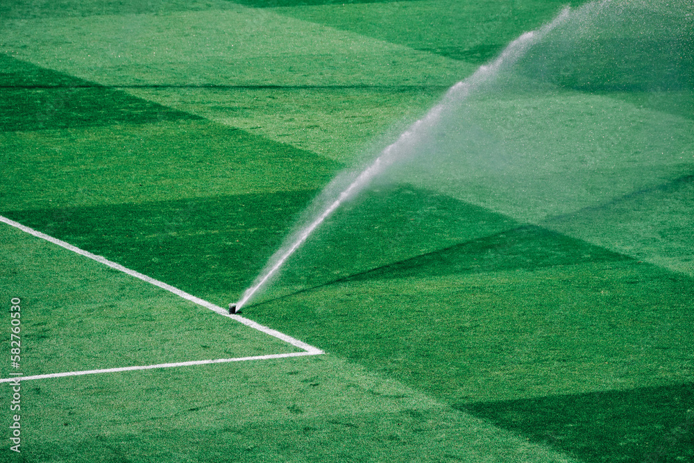 Keeping the pitch perfect: sprinkler in action on a hot day - obrazy, fototapety, plakaty 