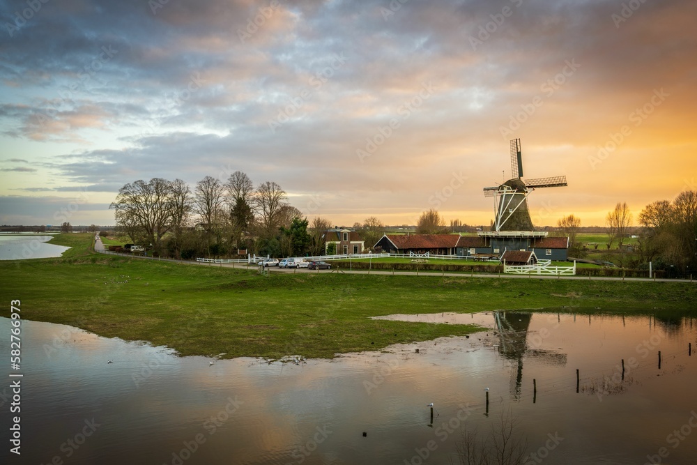 Scenic view of an old windmill with reflection on the water surface in the countryside