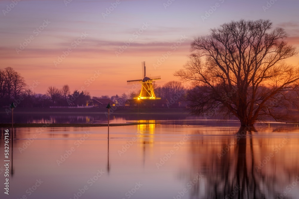 Scenic view of a calm waters with luminated old windmill in the background