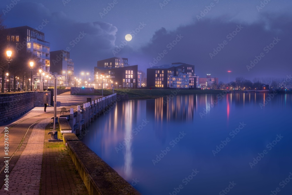 Scenic view of a walkway along a calm coast against city skyline