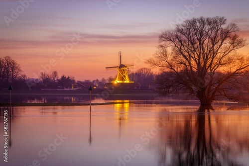 Scenic view of a calm waters with luminated old windmill in the background