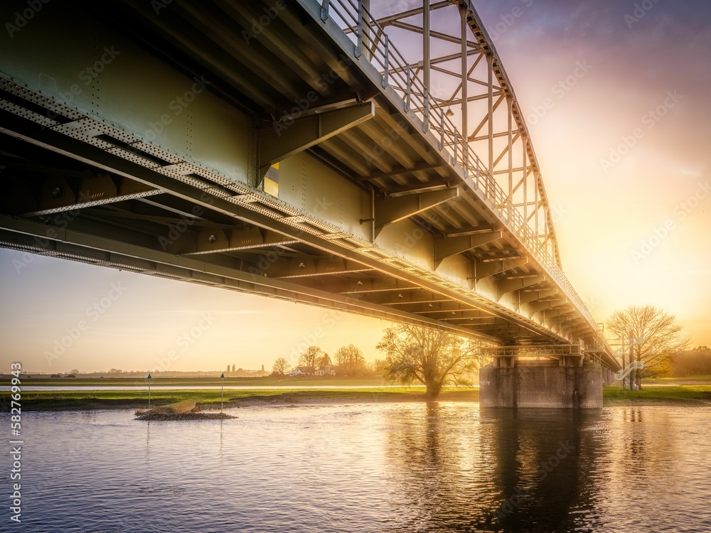 Metal bridge over a river captured against the bright sunset sky Metal bridge over a river captured against the bright sunset sky