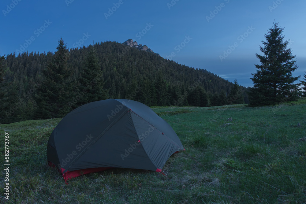 Tent on mountain col  in grass in the evening. On background Velky Rozsutec. Mala Fatra mountains,  Slovakia.