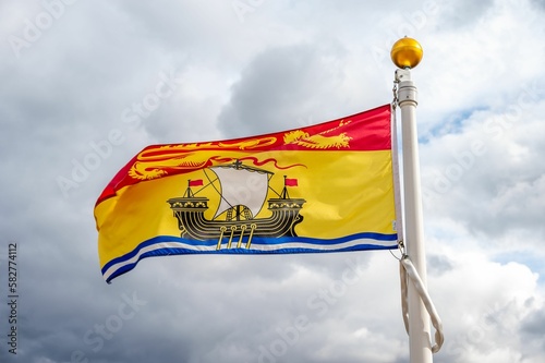 Flag of the New Brunswick in Canada against a cloudy sky
