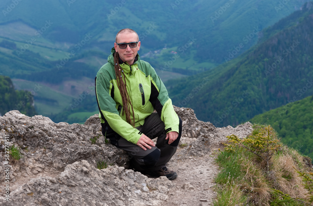 Hiker with dreadllocks on Maly Rozsutec, on background mountain village, Mala Fatra, Slovakia in spring cloudy morning