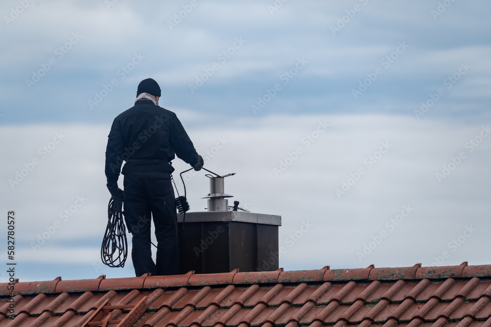 Ταπετσαρία Chimney sweep cleaning a chimney standing on the house roof, lowering equipment