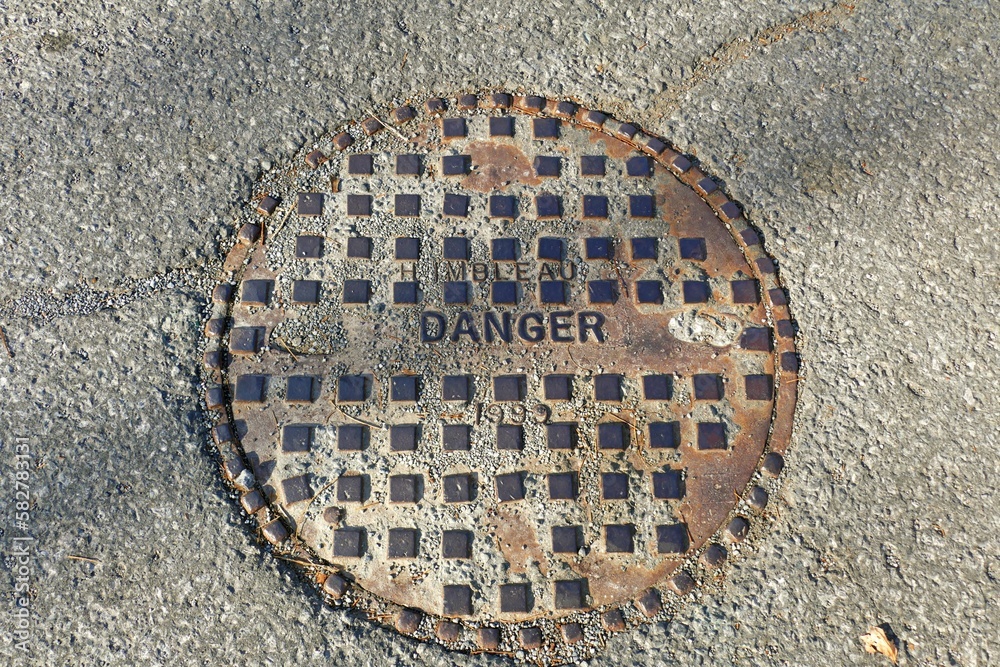 Top view of a manhole cover with the sign of danger on it