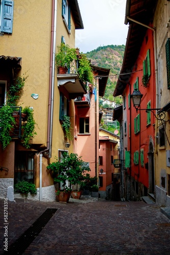 Fototapeta Naklejka Na Ścianę i Meble -  Vertical shot of a narrow street with old buildings decorated with plants in Argegno, Italy