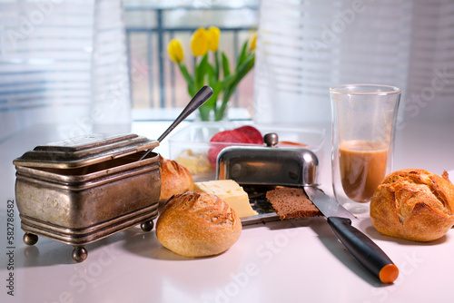 delicious breakfast on table fresh buns knife half cup of drunk coffee double bottomed glass cup rare sugar bowl yellow tulips bread butter breakfast rest rush to work leave everything on the table photo