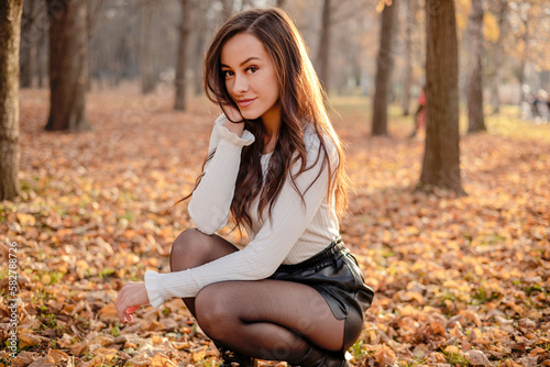A captivating image featuring a beautiful brunette woman in the backdrop of a scenic fall park, radiating autumnal charm and natural beauty