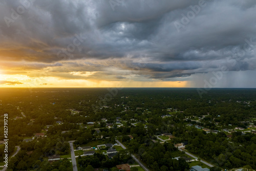 Landscape of dark ominous clouds forming on stormy sky during heavy thunderstorm over rural town area at sunset