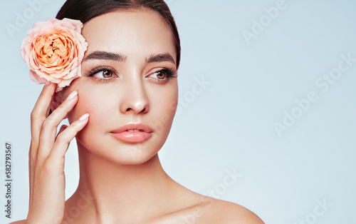 Portrait beautiful young woman with clean fresh skin. Model with healthy skin, close up portrait. Cosmetology, beauty and spa. Girl with a rose flower photo