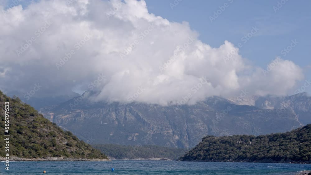 The static view of the sea, Mountain peaks behind, and a large cloud. Soothing landscape The static view of the sea, Mountain peaks behind, and a large cloud. Soothing landscape