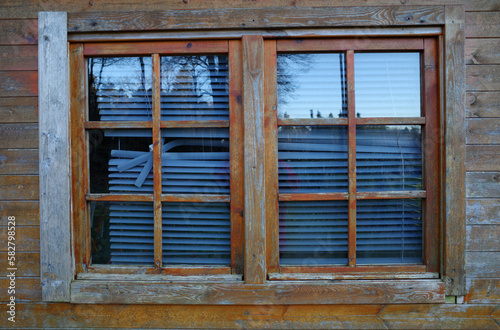 A window in a garden shed with broken blinds. The stained wood has also seen better days