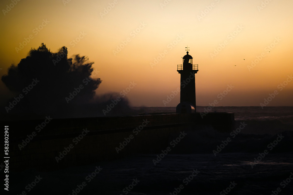 A huge wave at the lighthouse at dusk. Atlantic, Portugal.