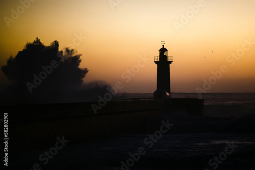 A huge wave at the lighthouse at dusk. Atlantic, Portugal.