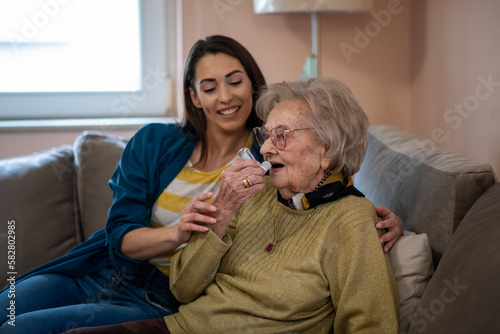 Young nurse caretaker helping grandma with her inhaler. photo
