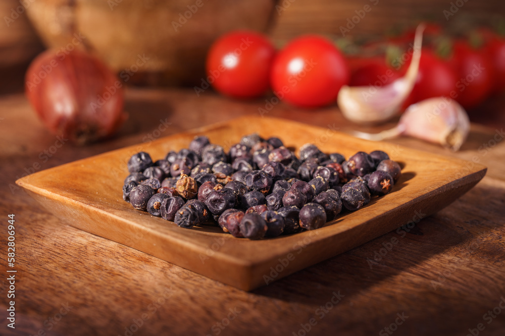 Fototapeta premium Owoc jałowca w drewnianej miseczce na rustykalnym tle