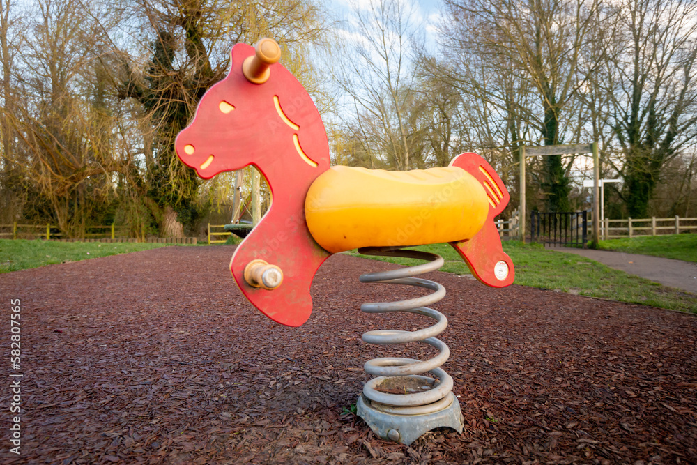 Colourful children's rocking horse on springs over wood chip floor in