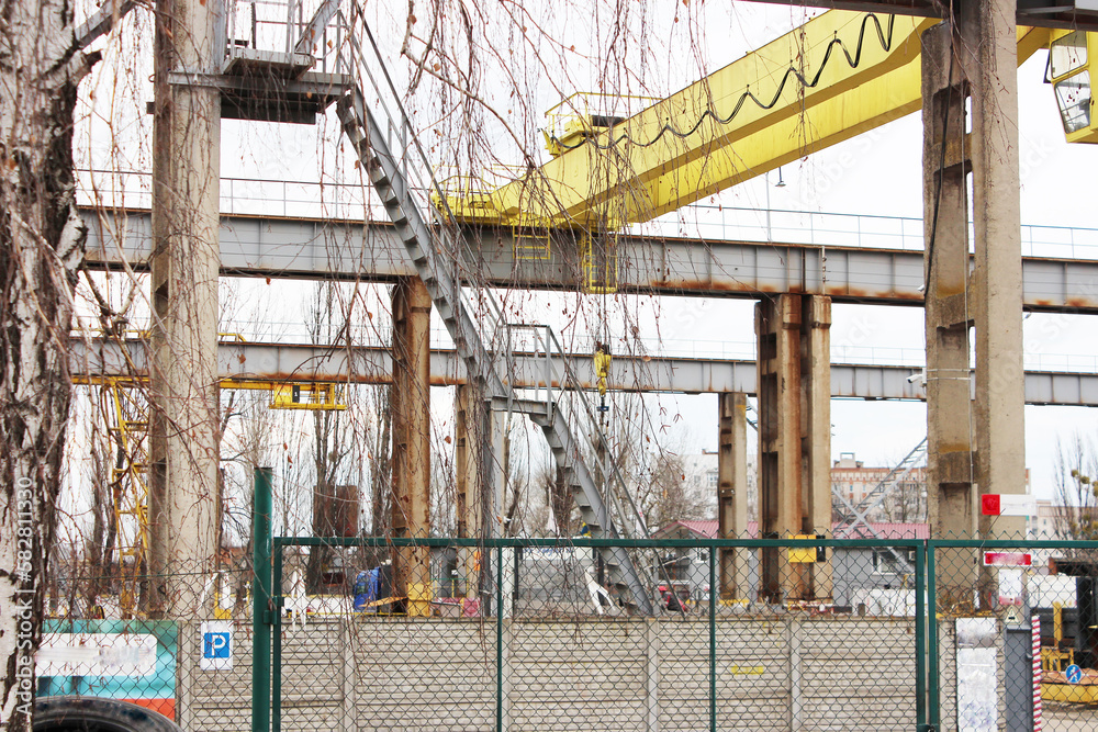 Factory overhead crane, yellow. concrete crane feet. industrial crane, industrial area. metal ladder