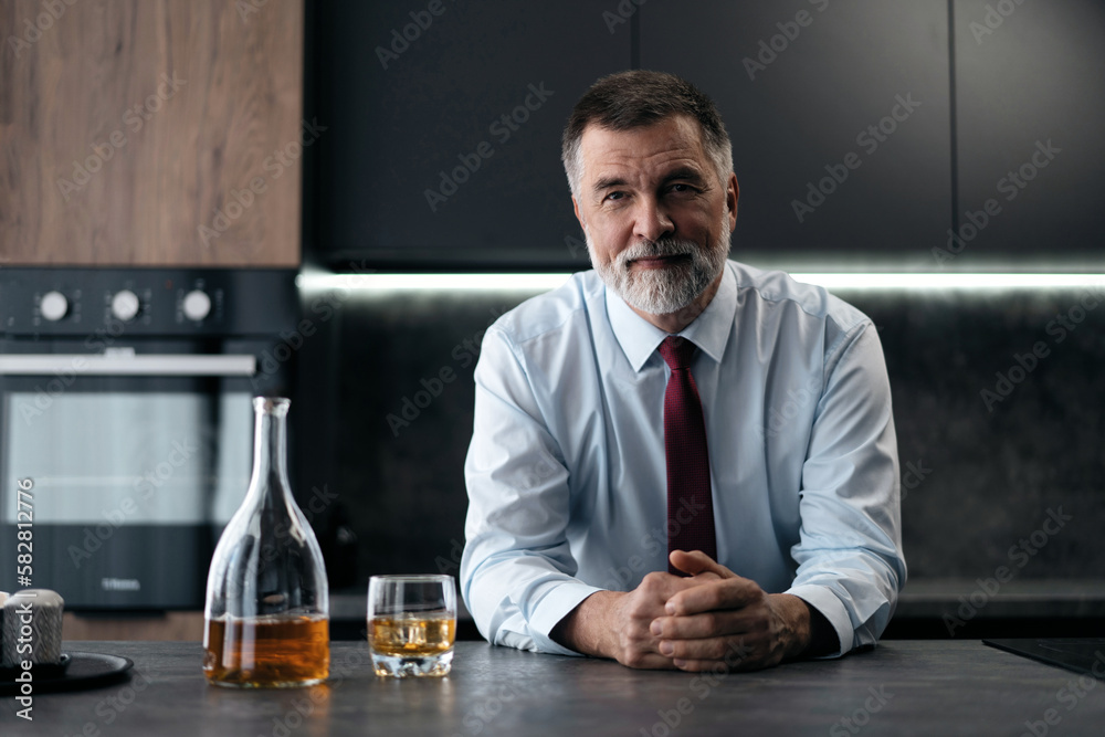 Confident rich mature wealthy businessman chilling relaxing drinking enjoying whiskey in the kitchen after work. Confident rich mature wealthy businessman chilling relaxing drinking enjoying whiskey in the kitchen after work.