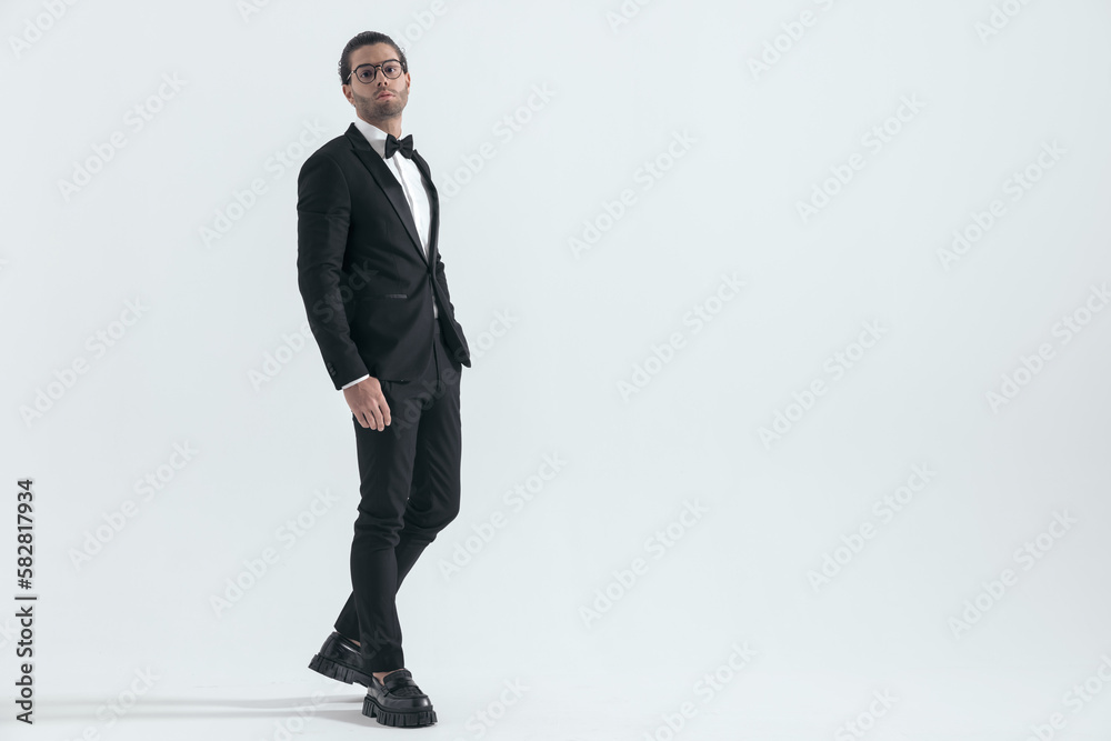 side view of handsome young groom with hand in pockets walking side view of handsome young groom with hand in pockets walking