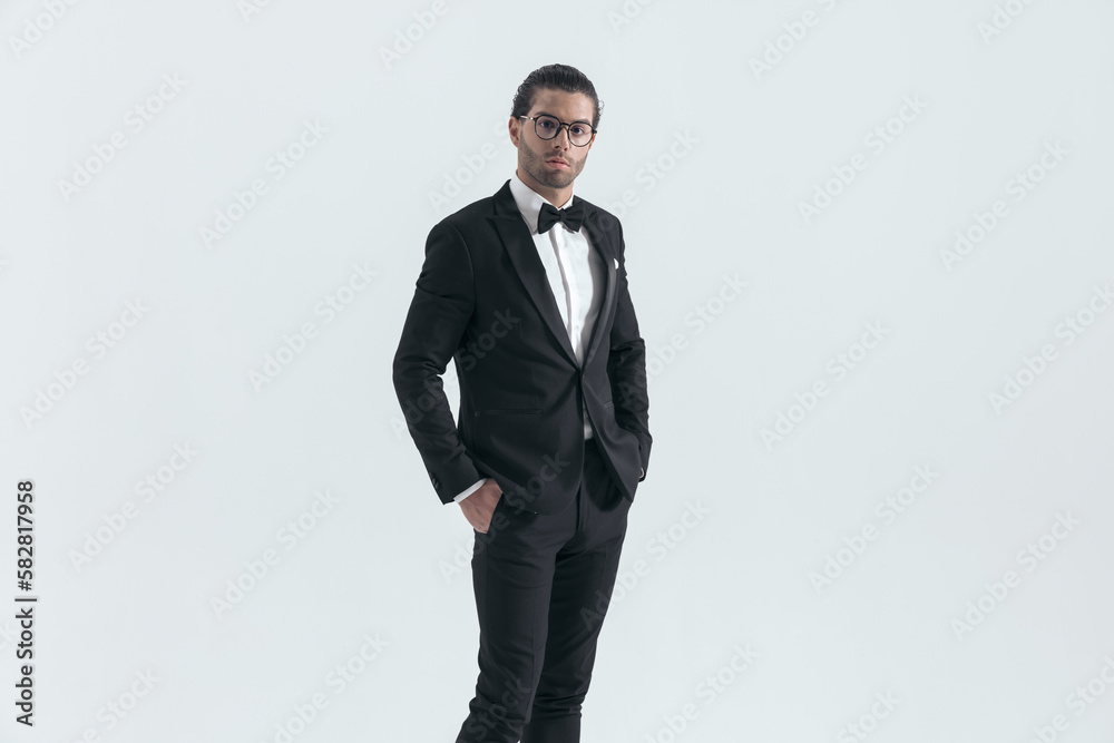 elegant groom with glasses posing with hands in pockets elegant groom with glasses posing with hands in pockets