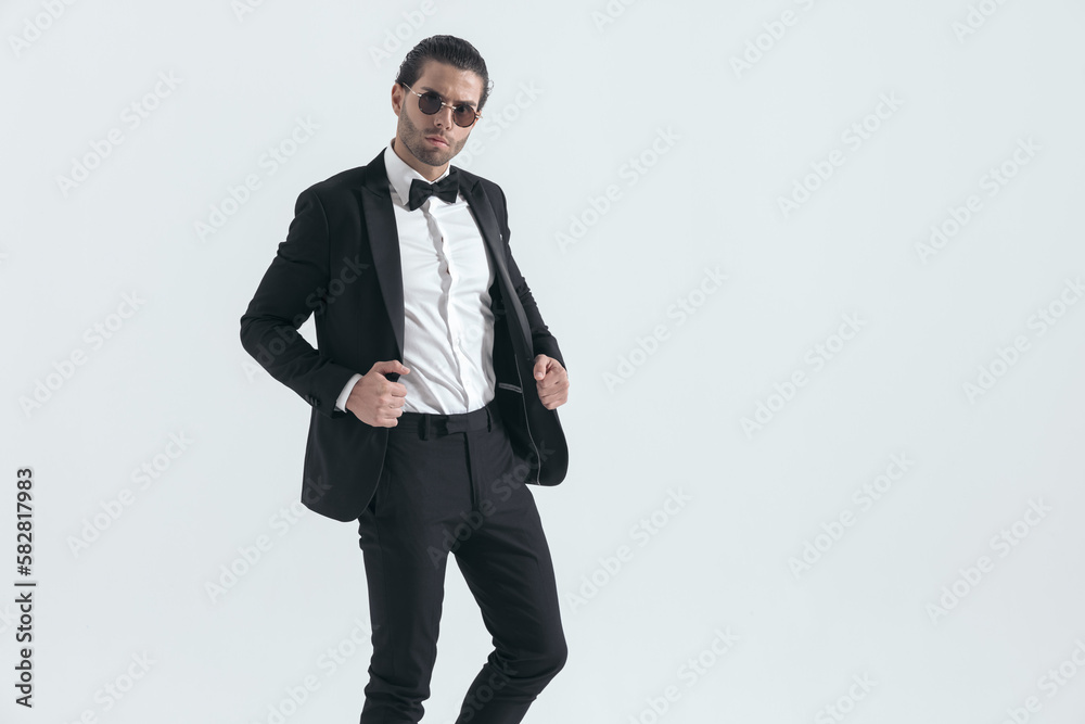 elegant young man with glasses adjusting black tuxedo jacket elegant young man with glasses adjusting black tuxedo jacket