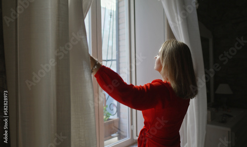 Woman opening curtains in her apartment.