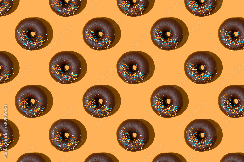 Chocolate donuts pattern isolated on orange background. Bakery, doughnut, treat, sweet food. Top view, flat lay, wallpaper, backdrop