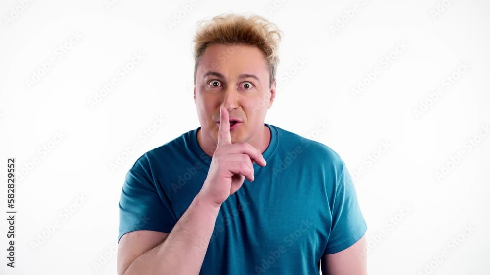 Secret, mystery and man keeps index finger on lips, makes silence gesture. Positive expression, confident smiling guy looks around in studio isolated on white background. Secret, mystery and man keeps index finger on lips, makes silence gesture. Positive expression, confident smiling guy looks around in studio isolated on white background.