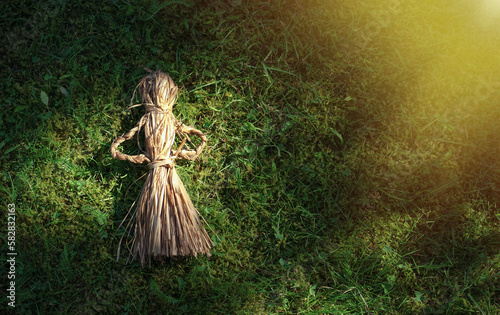 A woven doll made of dry grass lies on the ground. Old ways of making toys in ancient times. Transfer of weaving knowledge from generation to generation.A toy made of reeds. © Svetliy