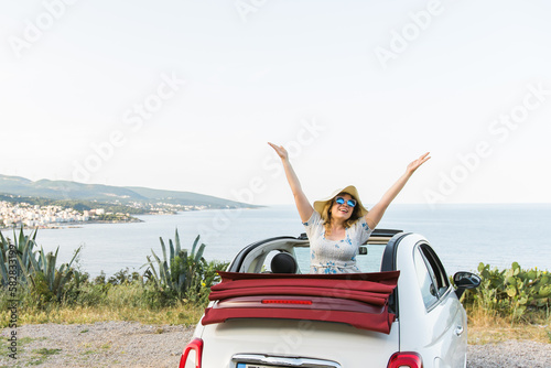 Young woman having fun in cabrio against a beach and sea copy space and empty place for text - travel and summer voyage nature concept