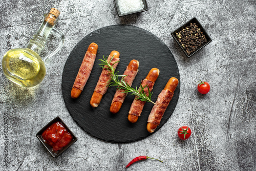 sausages wrapped in bacon, grilled on a stone background