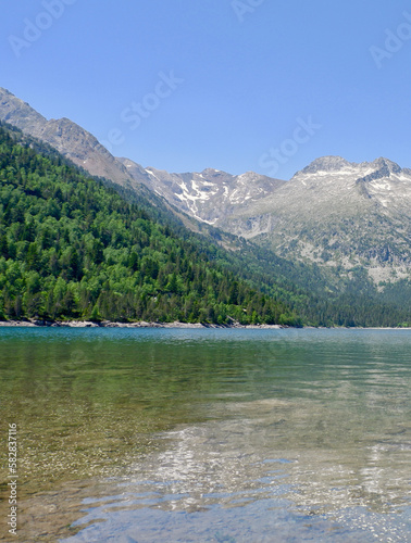Translucent calm tranquil water of Lake Oredon in the mountains and the peak Nouvielle. Peaceful landscape of Pyrenean Mountain Range, France. Vertical photo