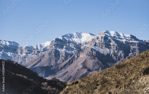 Panorama of a mountain range from layers of rocks with the first snow on the rocks and slopes, autumn mountains with the first snow