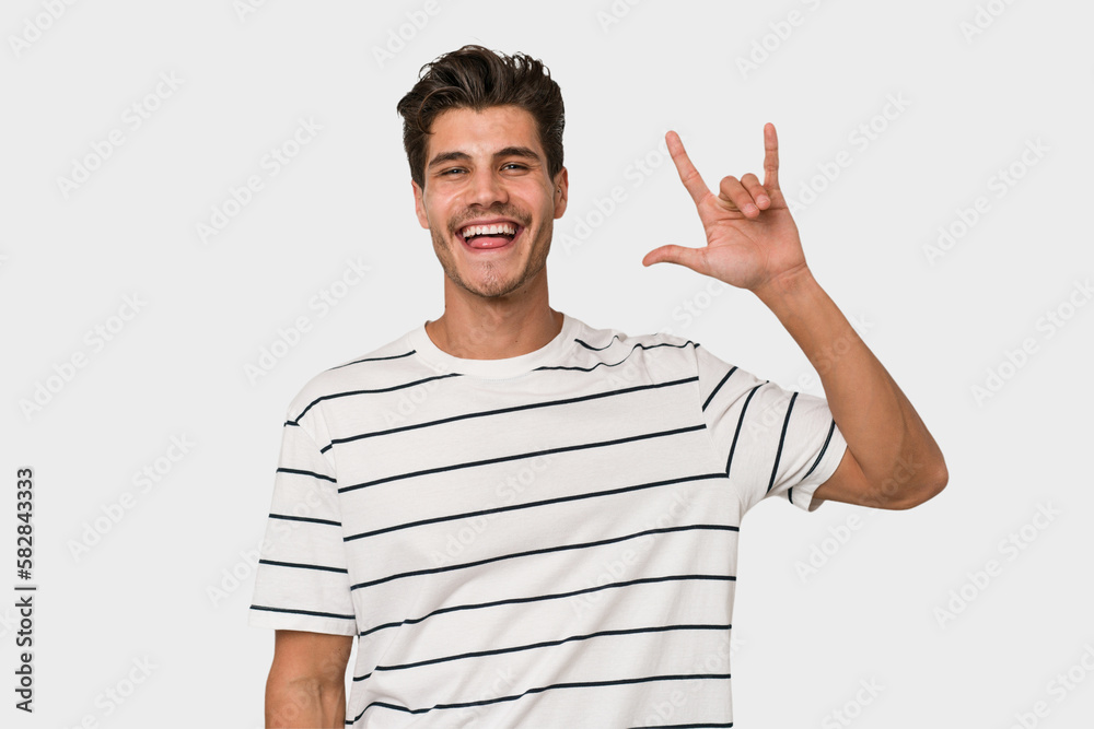 Young handsome caucasian man isolated on white background showing a horns gesture as a revolution concept. Young handsome caucasian man isolated on white background showing a horns gesture as a revolution concept.