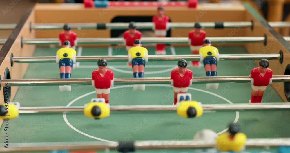 Close-up of foosball players figurines trying to kick ball . People play mini foosball and score a goal with a ball into the goal.slow motion Close-up of foosball players figurines trying to kick ball . People play mini foosball and score a goal with a ball into the goal.slow motion