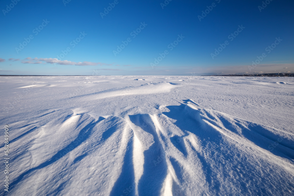 View of the snow-covered frozen lake. Ice fragments close-up. Winter landscape.