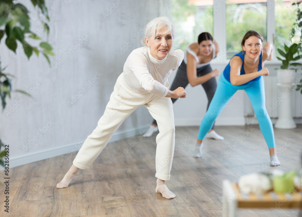 Φωτογραφία Cheerful sporty senior woman training movements of rhythmic latin zumba with group in fitness studio