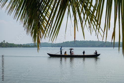 People on a boat framed by palm fronds. Kerala, India.