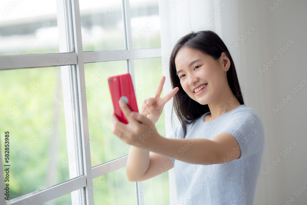 Happiness young asian woman video call with smartphone in the living room at home, female smiling and using social media online with smart phone at home, lifestyles and communication concept. Happiness young asian woman video call with smartphone in the living room at home, female smiling and using social media online with smart phone at home, lifestyles and communication concept.