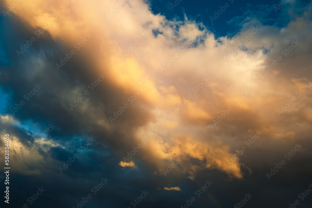 Dramatic sky. Dark cumulus clouds in sunlight on a blue background. After storm. Sunny evening. Cleared up. Beauty of thunderstorm, hurricane or storm. Air element. Wallpaper. Moving ciclone. Heaven