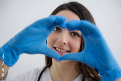 beautiful girl nurse showing heart in blue gloves doctor surgery helping people care treatment hippocratic oath love