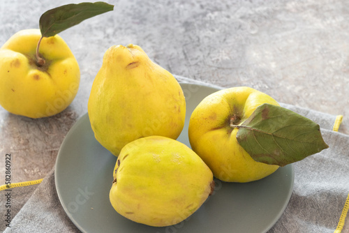 Ripe bio quince pear fruits with leaves on a modern style plate and kitchen table. Cydonia oblonga