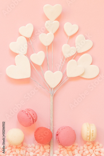 Heart shaped tree dessert in flat lay design with premium pastel colored macaroons and candy. © littlehandstocks
