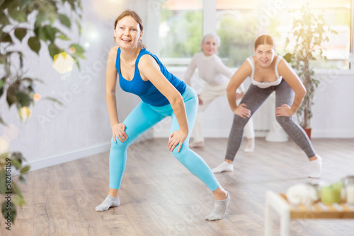 Adult woman in sportswear performs dance moves in fitness center