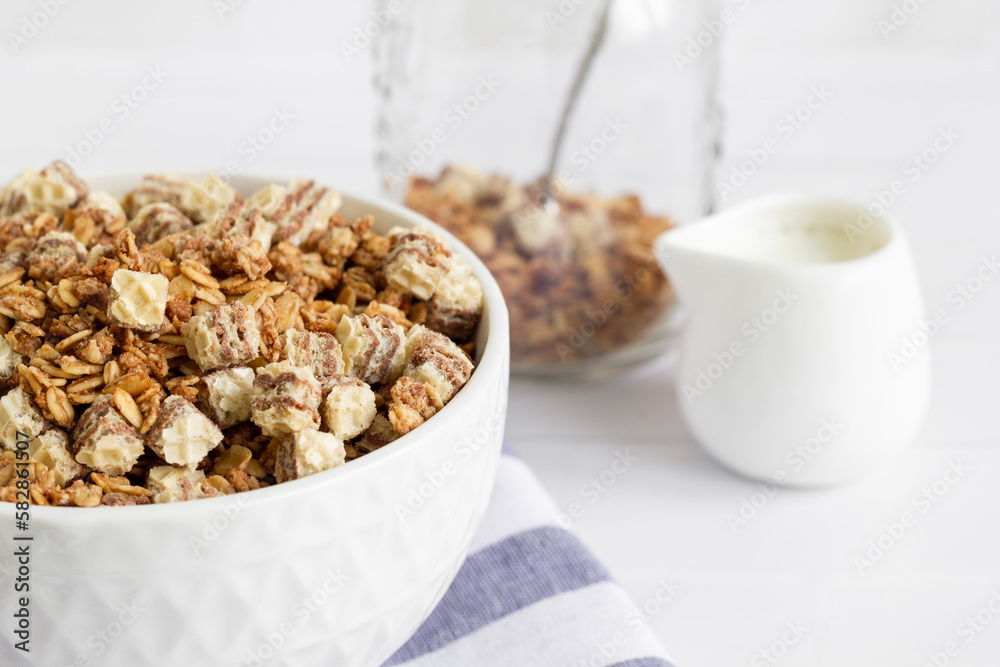 Home made breakfast bowl with granola, muesli and milk. White toned image of a delicious breakfast plate with cereal jar in the background. Home made breakfast bowl with granola, muesli and milk. White toned image of a delicious breakfast plate with cereal jar in the background.