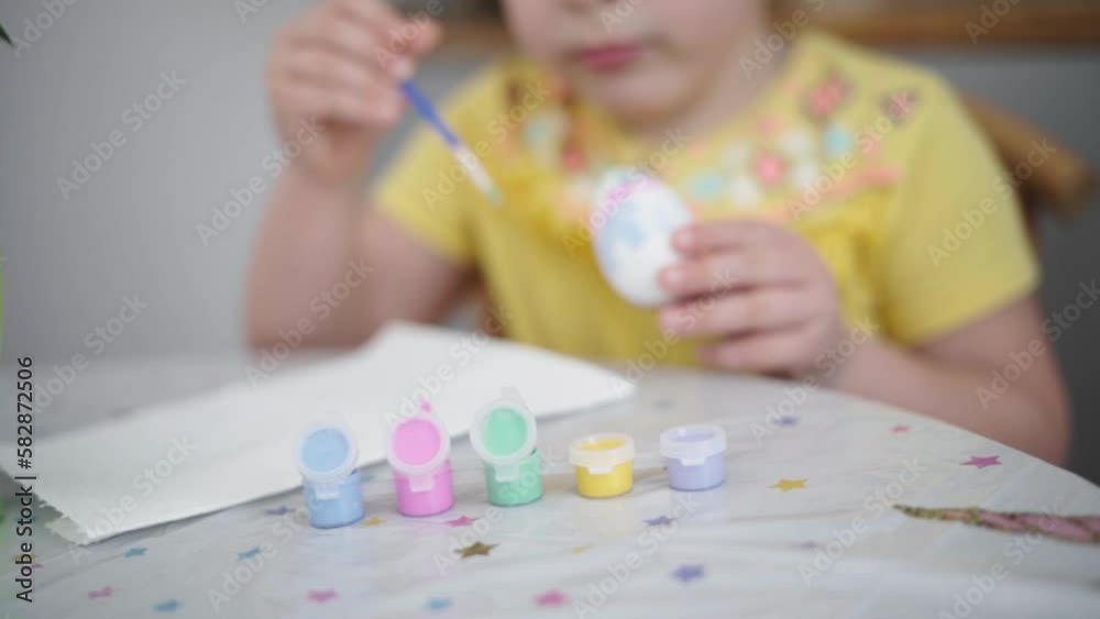 Child girl of preschool age painting Easter eggs at home kitchen. Easter spring traditions. Slow motion Child girl of preschool age painting Easter eggs at home kitchen. Easter spring traditions. Slow motion