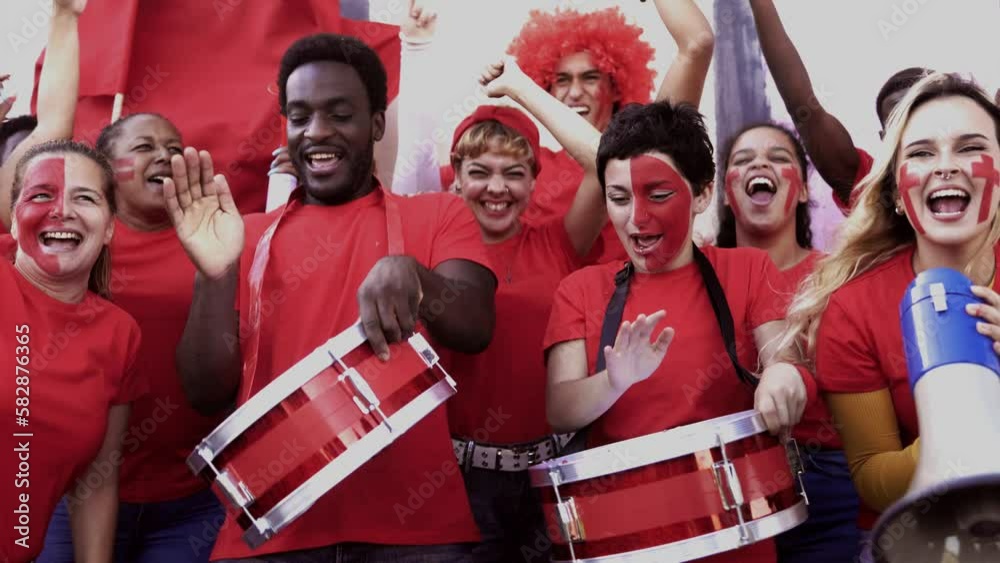 Crazy football fans celebrating in the crowd while watching the game at